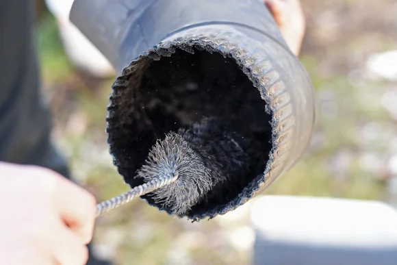 Reinigung eines Ofenrohrs mit Drahtbürste